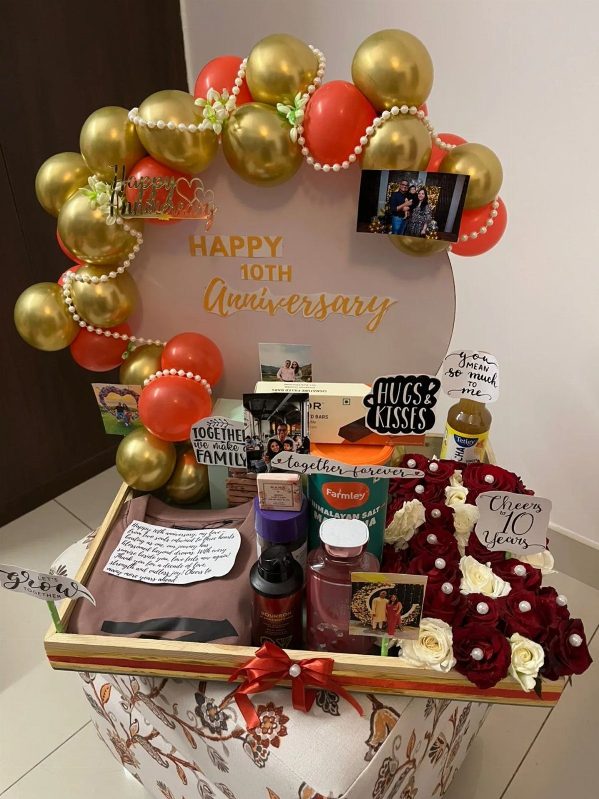 Anniversary gift hamper with gold balloons, red roses, and 10th anniversary signage.
