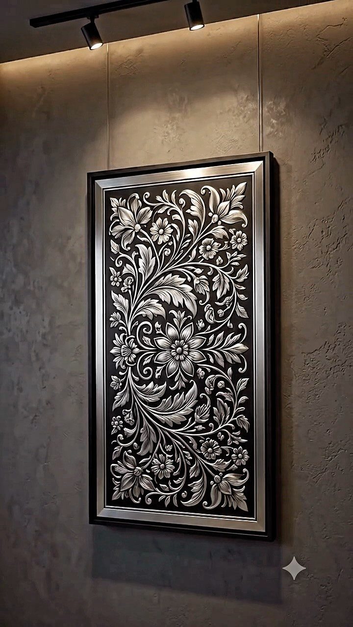 Silver embossed metal floral wall art in a black frame on a grey wall.