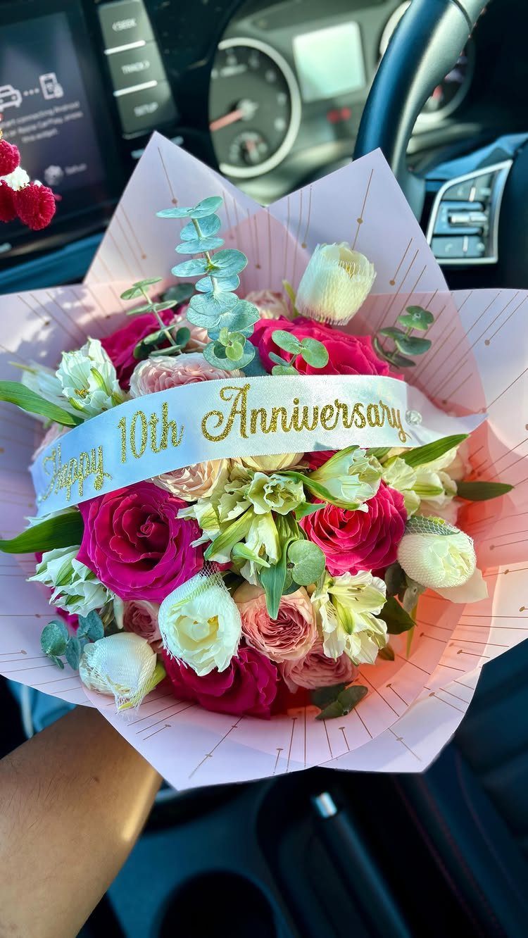 Bouquet of pink and red roses with a Happy 10th Anniversary ribbon.