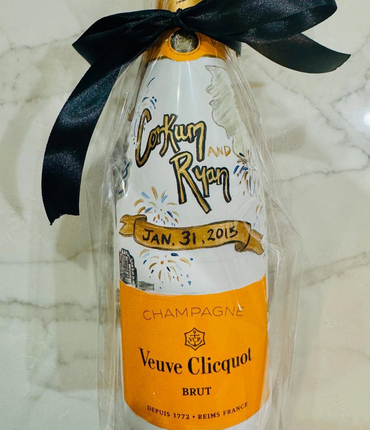 Veuve Clicquot Champagne bottle with custom anniversary label and black ribbon bow.