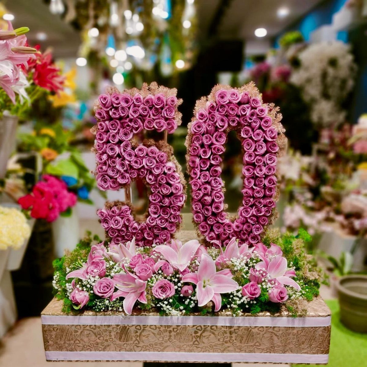 Pink rose floral arrangement shaped as the number 50 on a gold box.