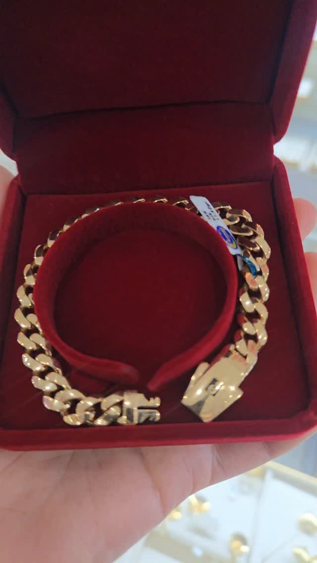 Gold curb link bracelet inside a red velvet jewelry box held by a hand