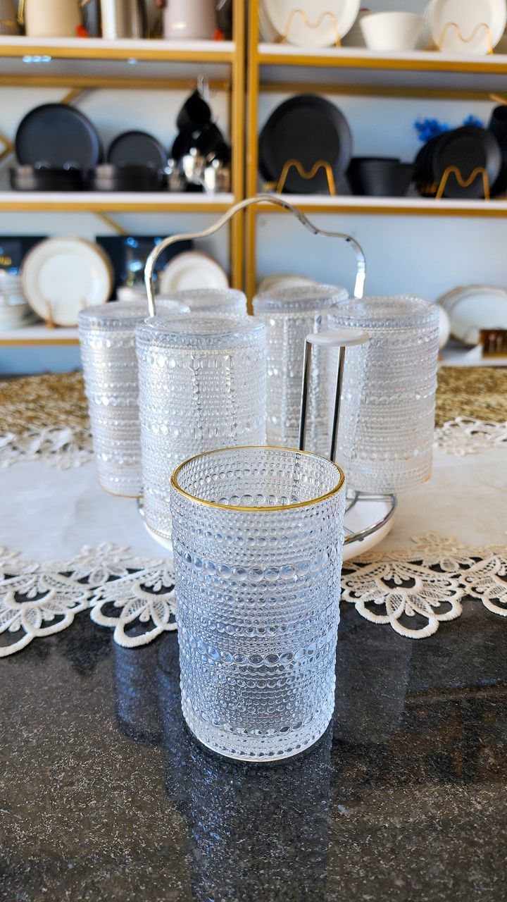 Textured clear glass tumblers with gold rims on a dark granite countertop.