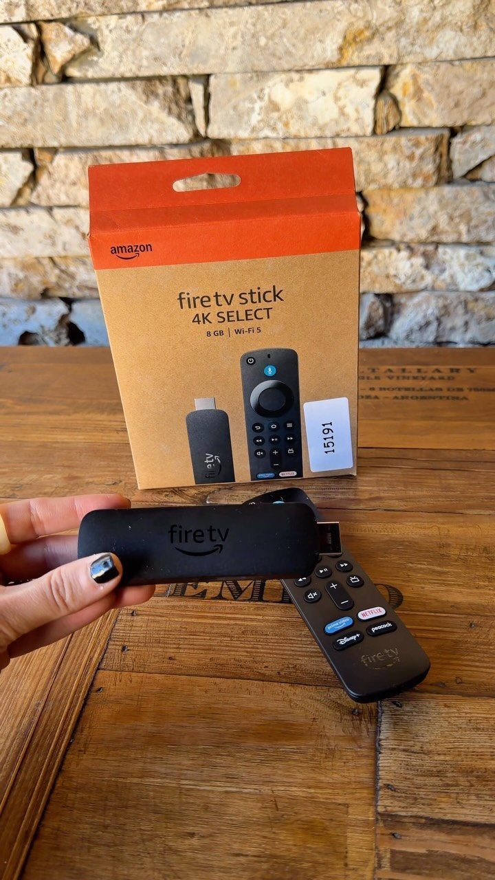 Amazon Fire TV Stick and remote next to its orange retail packaging box.