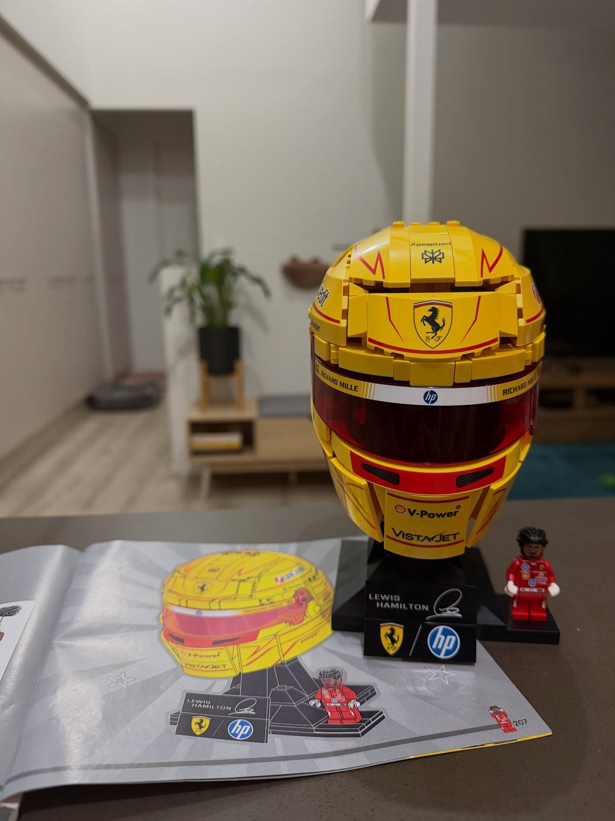 Yellow LEGO racing helmet on a stand with a small driver figure.