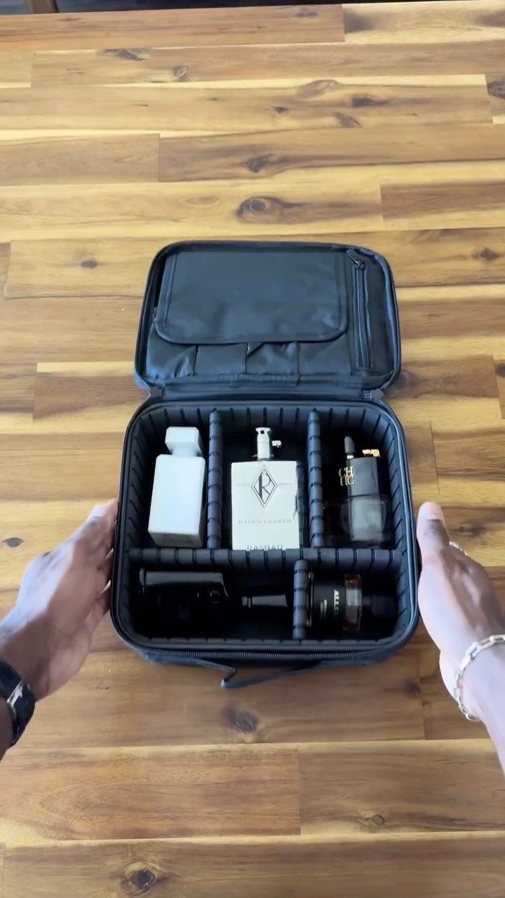 Cologne bottles in a black travel case held over a wooden table