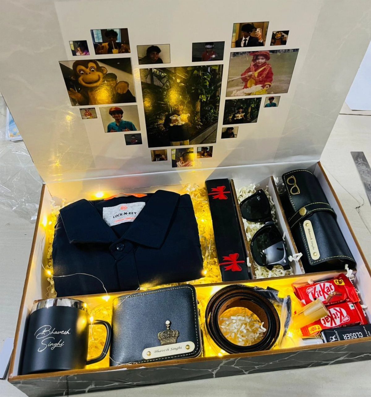 Gift box with black clothing, accessories, and a photo collage on the lid.