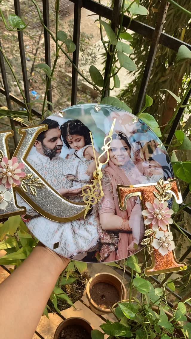 Customized circular photo clock with glittery letters and flowers held outdoors.