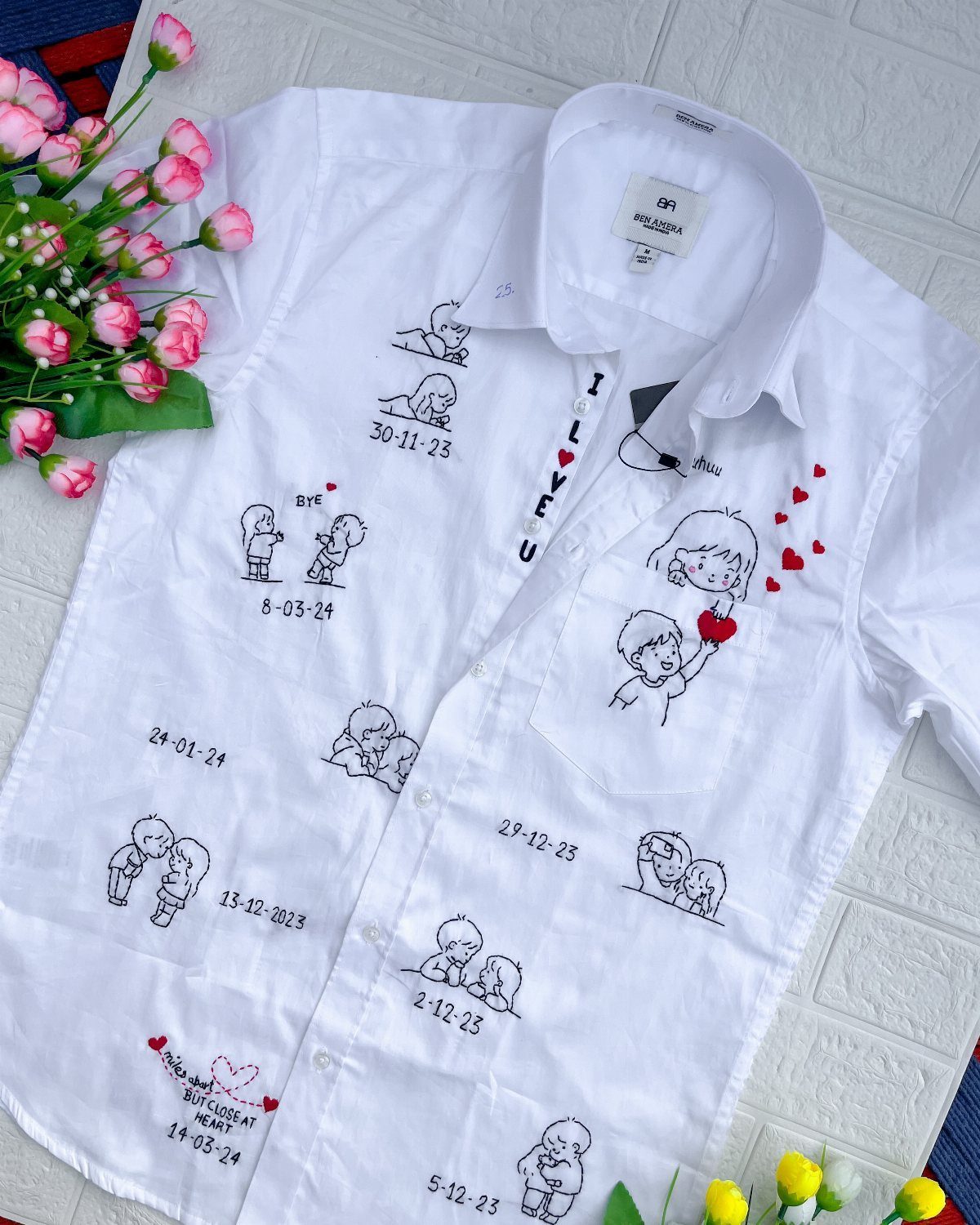 White button-down shirt with custom couple illustrations and dates on a brick background
