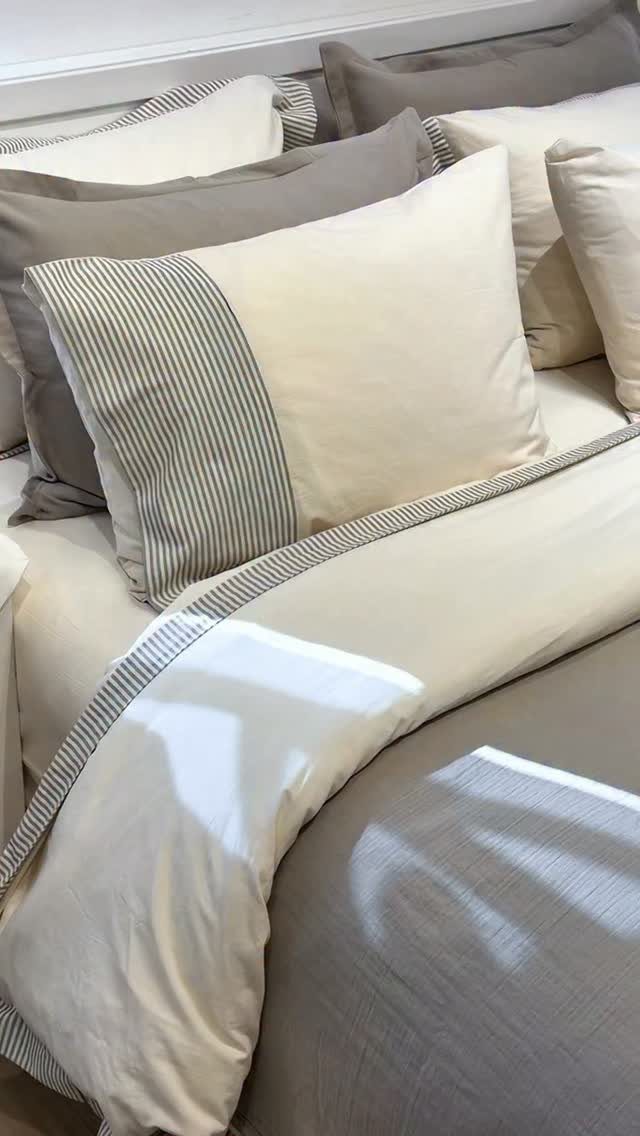 Cream and taupe linen bedding with striped accents on a cozy bed.
