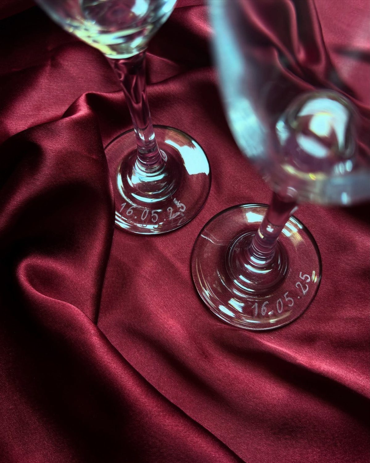 Engraved wine glass bases with a date resting on red satin fabric