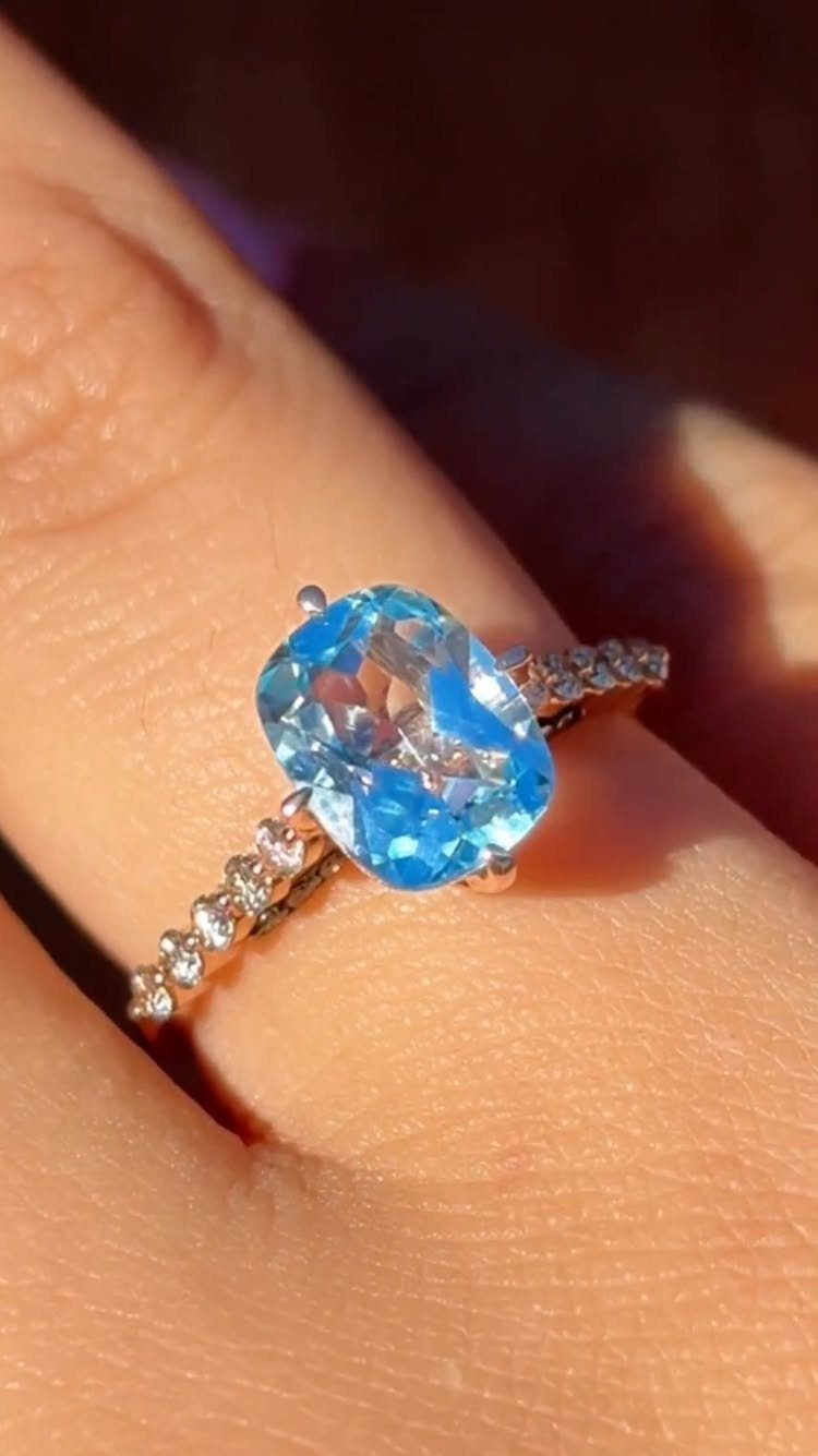 Silver ring with a large oval blue topaz gemstone on a finger