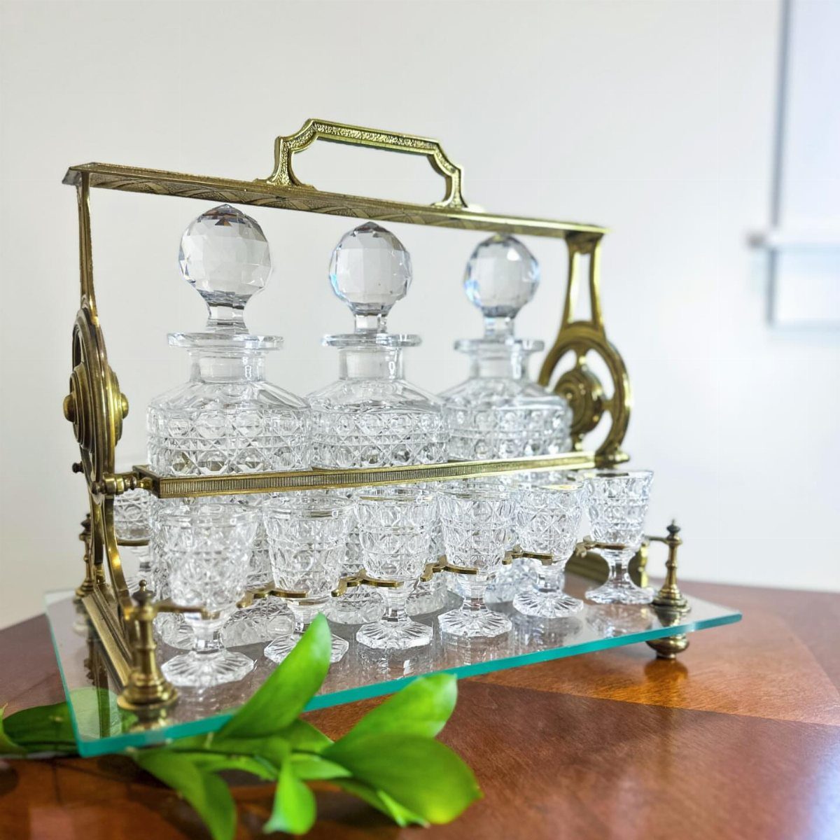 Vintage brass and crystal liquor set with decanters and glasses on a wooden table