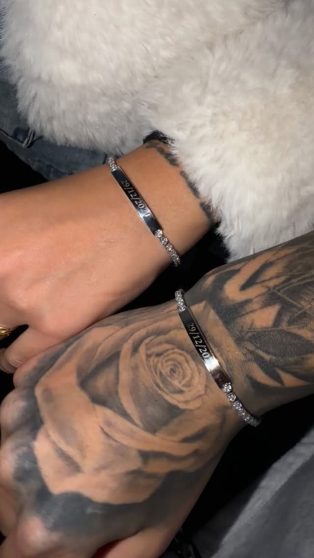 Two silver engraved bracelets with small diamonds worn on tattooed wrists.