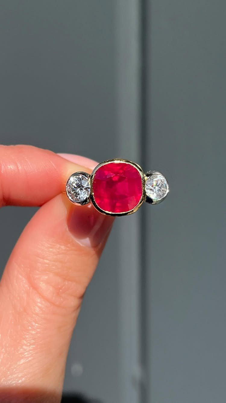 Gold ring with a central oval red ruby and two side diamonds.