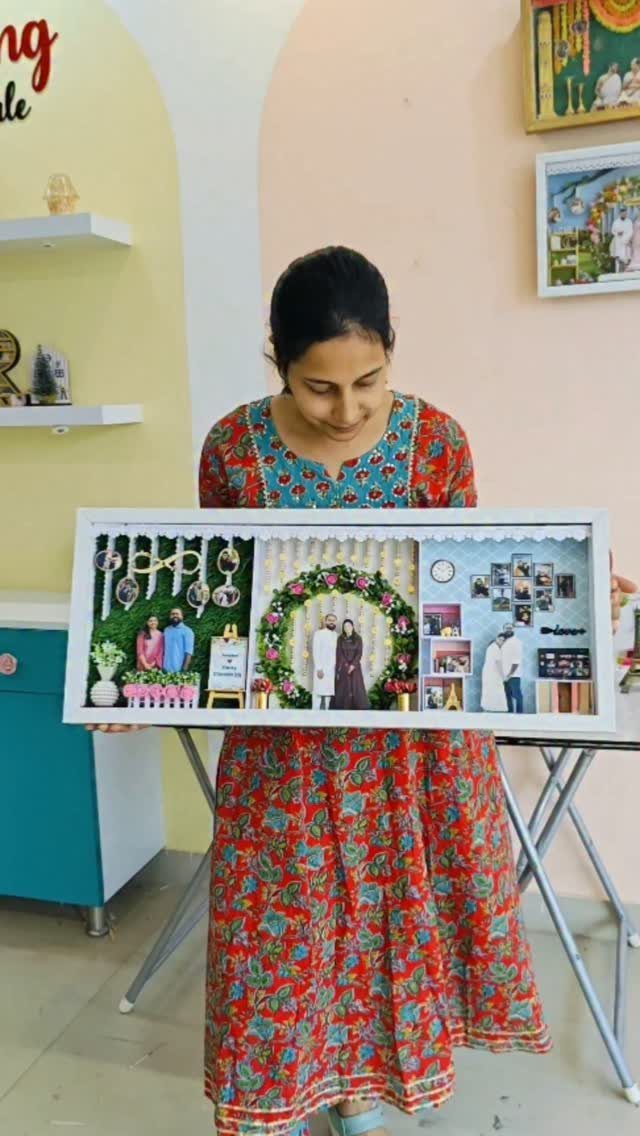Woman holding a personalized 3D shadow box frame with photos and floral decorations.