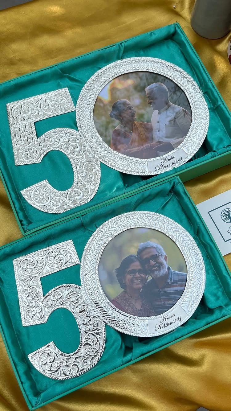 Silver number 50 frames with photos of a couple on green cushions.