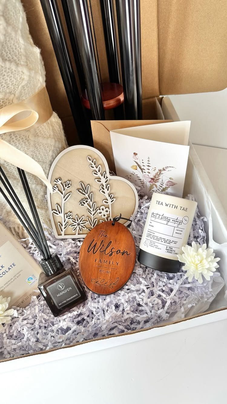 Gift box with personalized wooden heart, family name tag, candle, and knit blanket.
