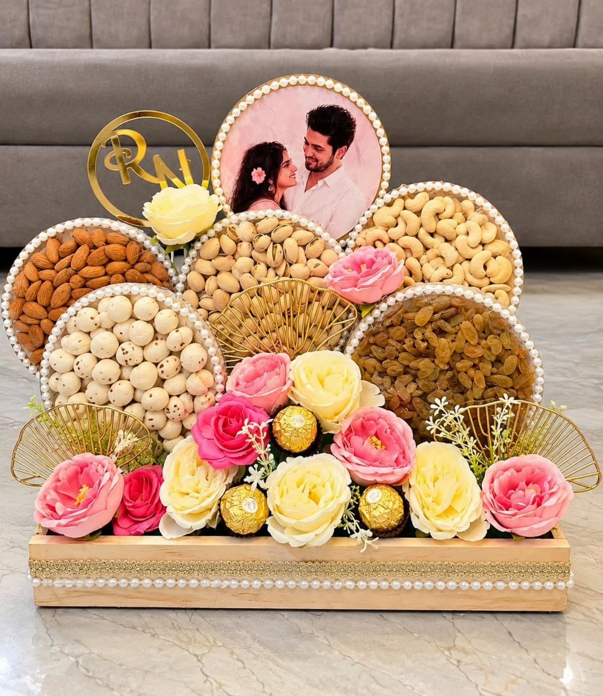 Decorative gift hamper with nuts, flowers, chocolates, and a framed couple's portrait.