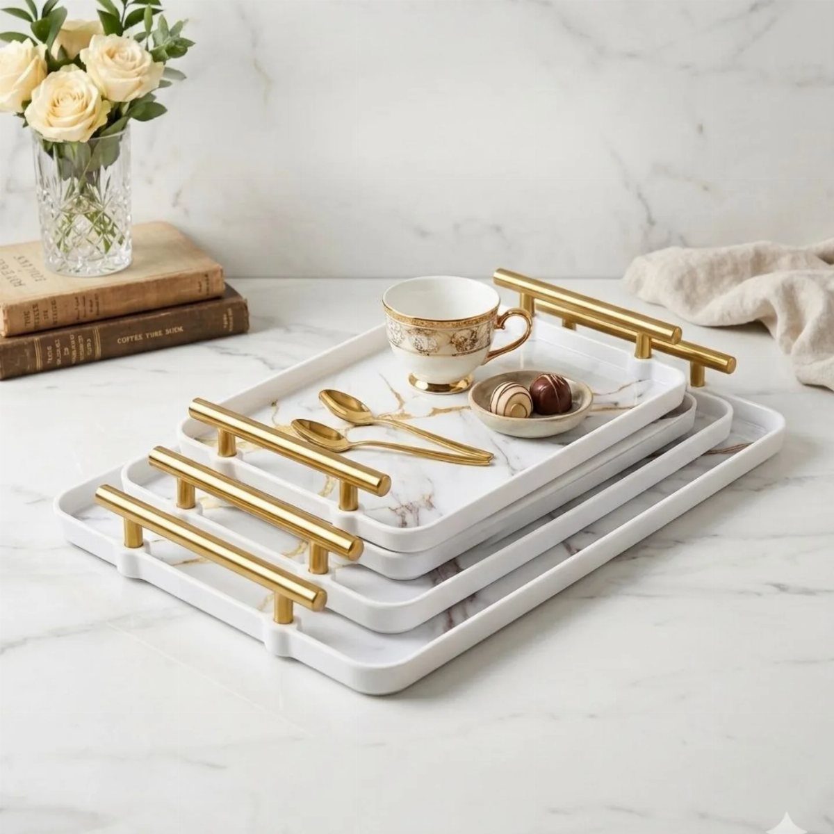 White marble serving trays with gold handles holding a teacup and chocolates.