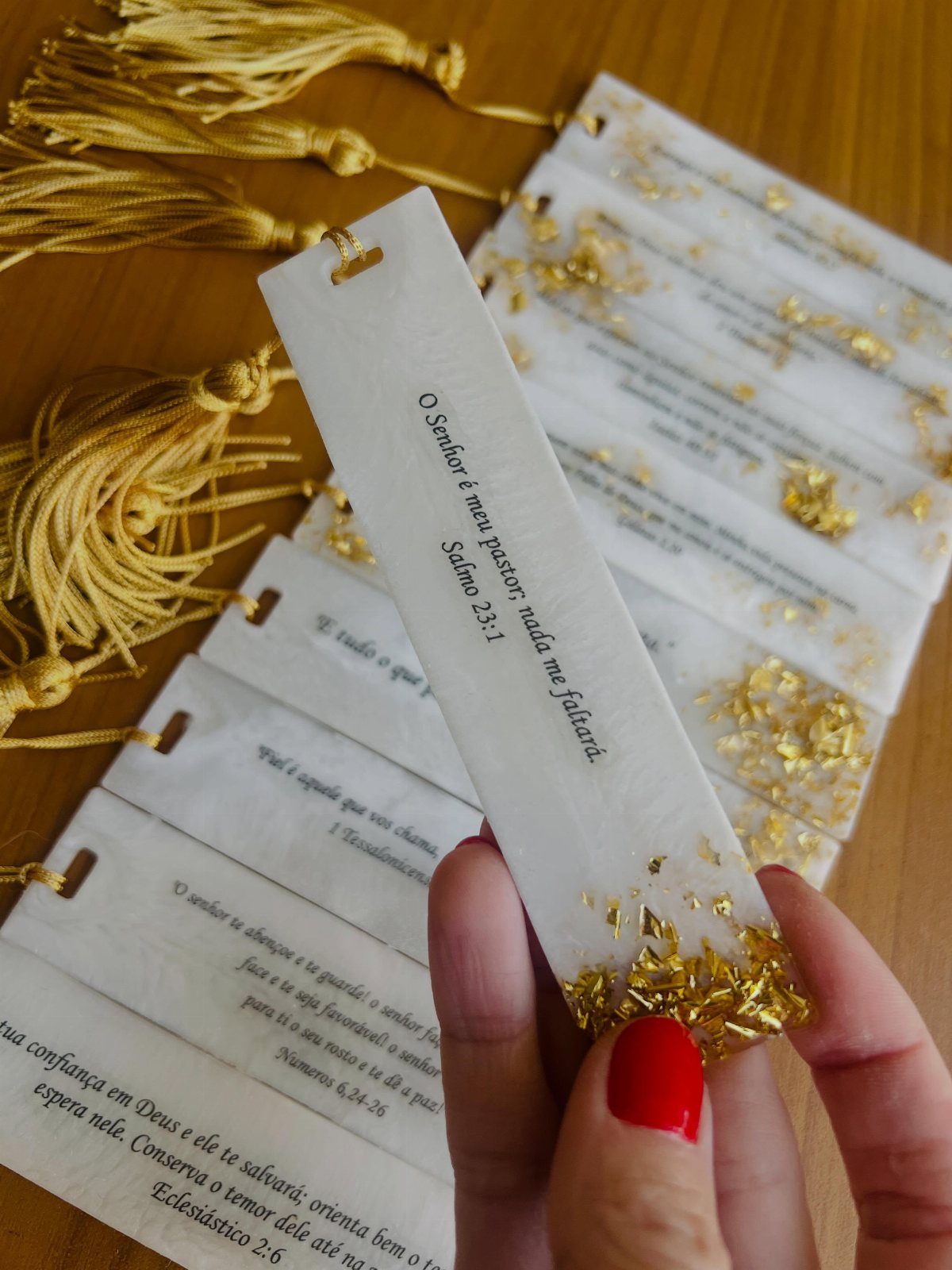White bookmarks with gold leaf accents and gold tassels on a wooden table
