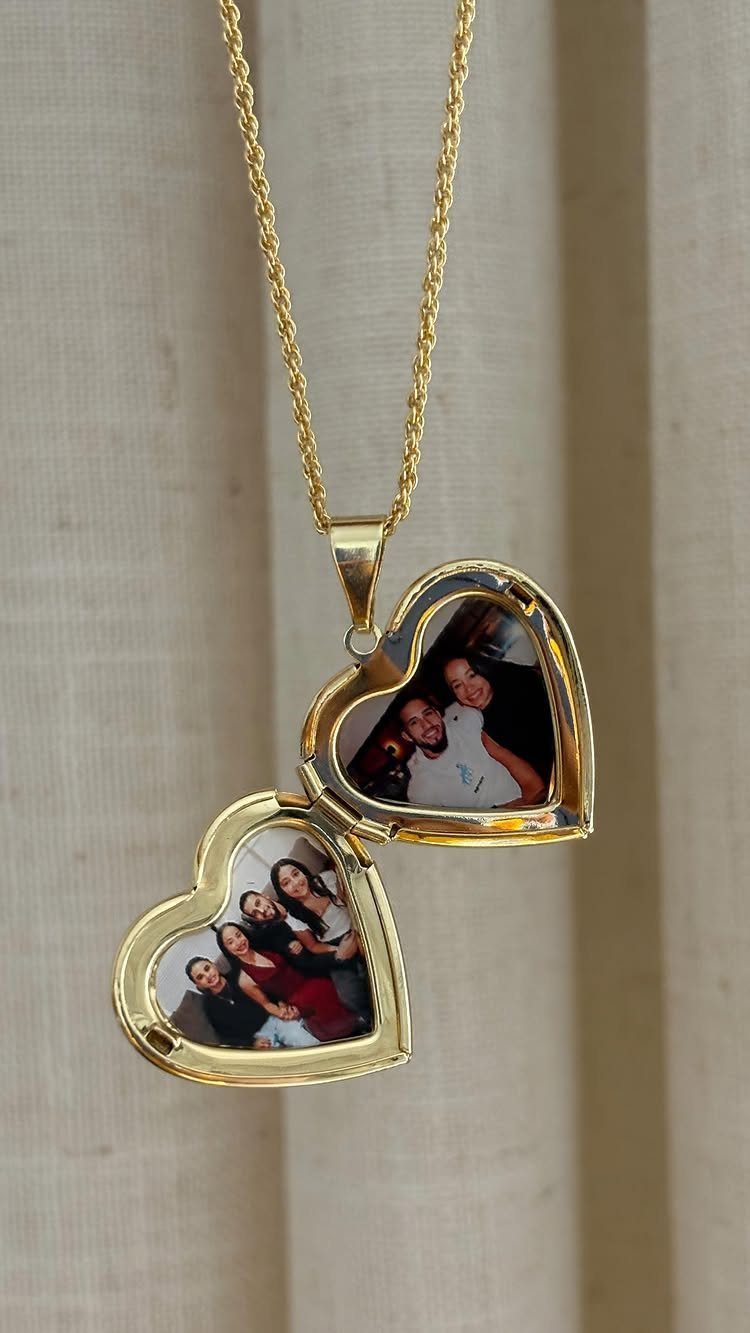 Gold heart-shaped locket necklace open to reveal two personal photographs inside.