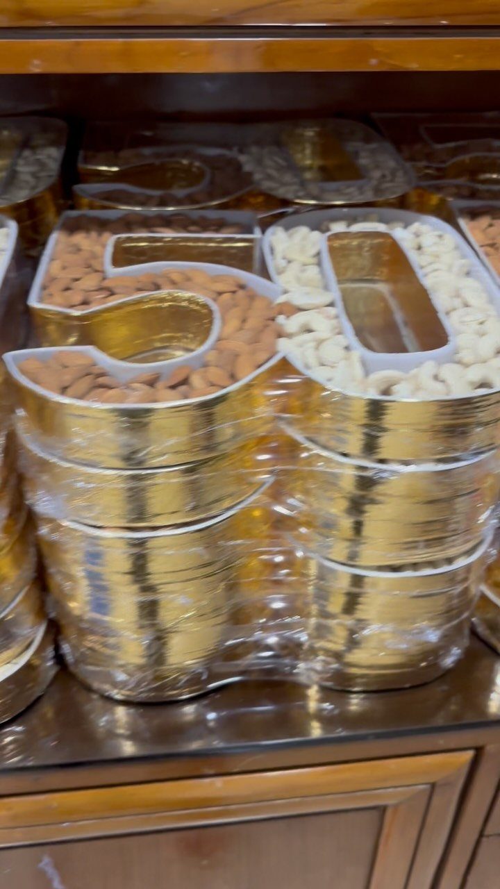 Gold number 50 containers filled with almonds and cashews on a shelf