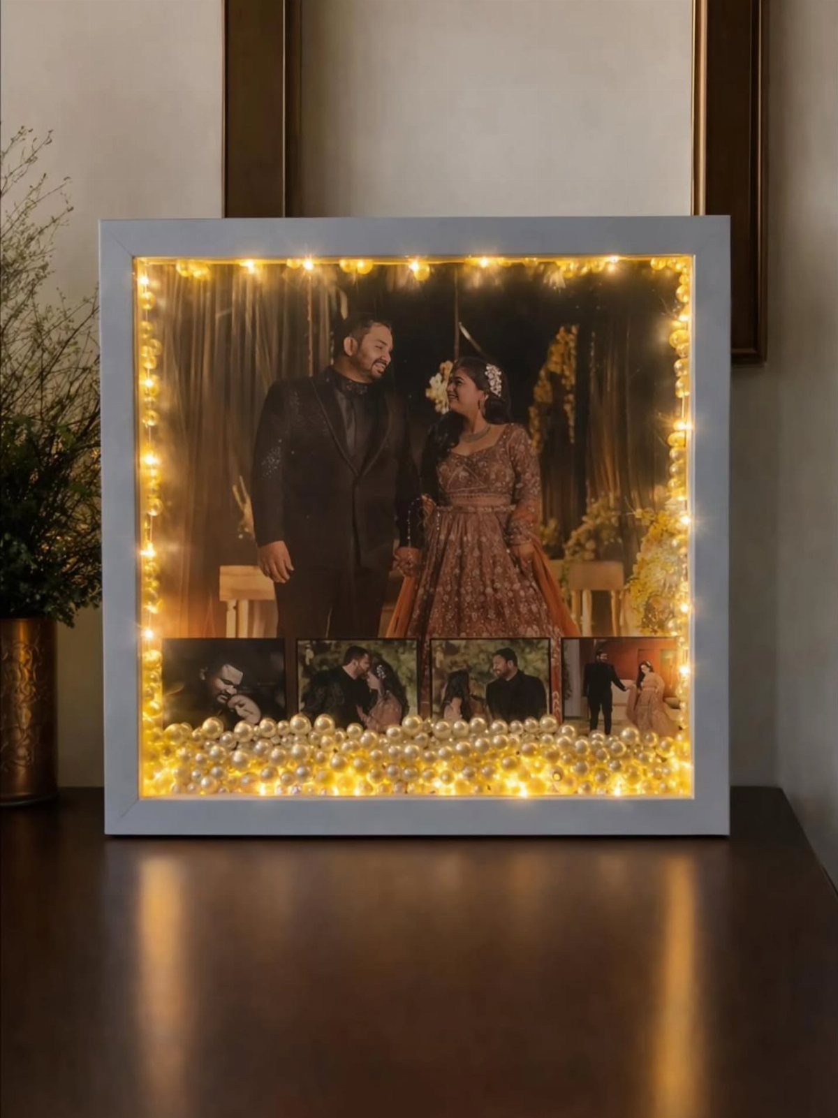 Illuminated white picture frame featuring a couple's photos and warm fairy lights.