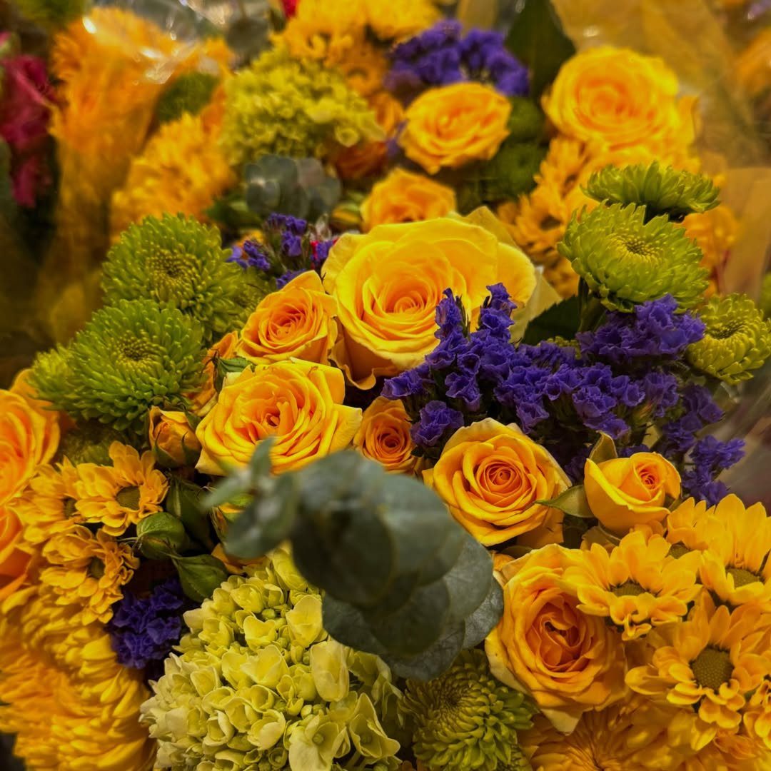 Yellow roses and purple statice flowers arranged in a vibrant anniversary bouquet.