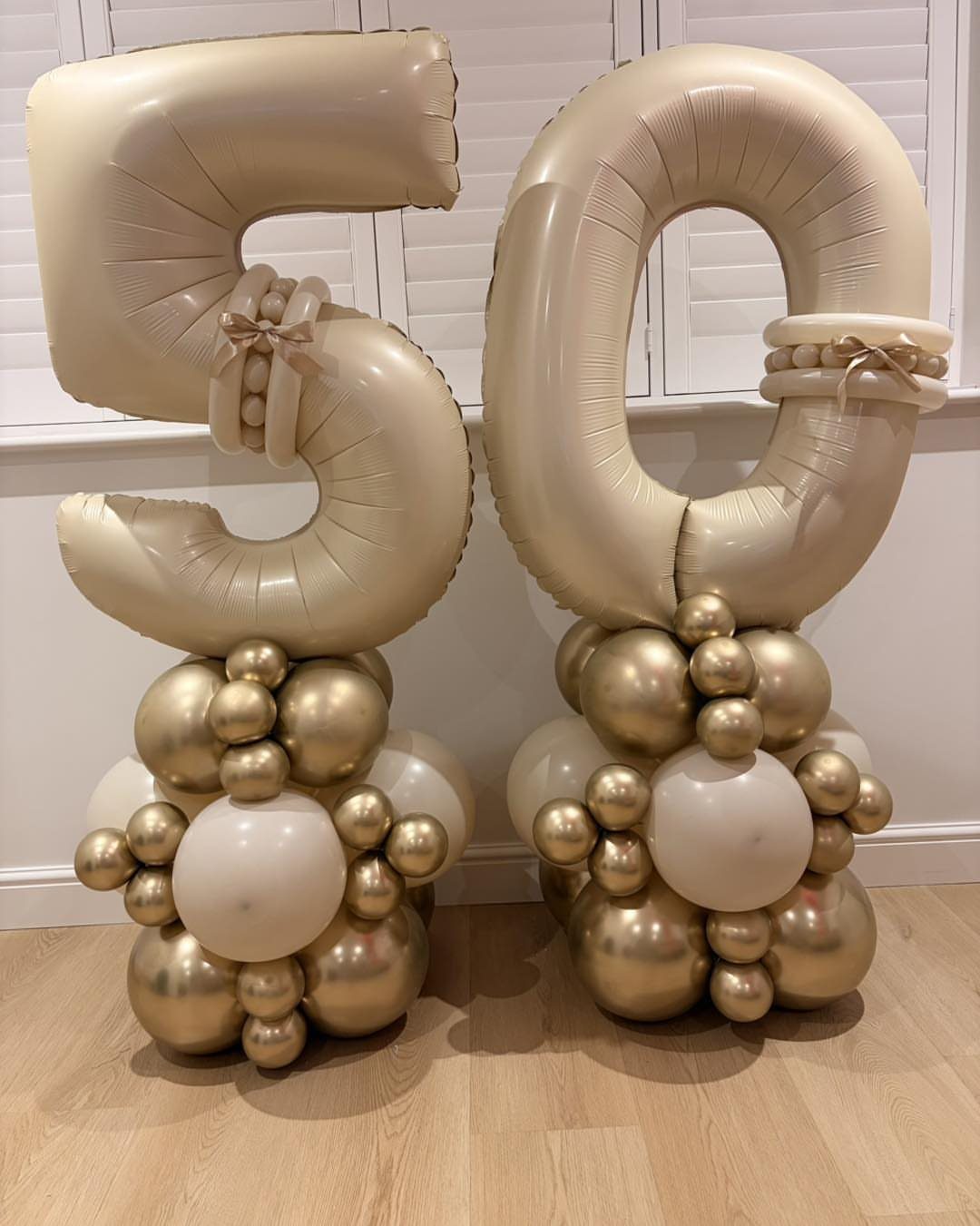 Gold number 50 balloons resting on clusters of gold and white balloons.