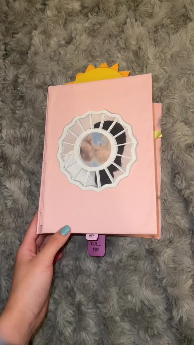 Handmade pink scrapbook with a couple's photo in a circular cutout on grey rug