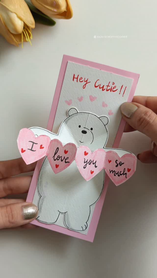 Handmade paper card with a white bear holding pink hearts saying I love you
