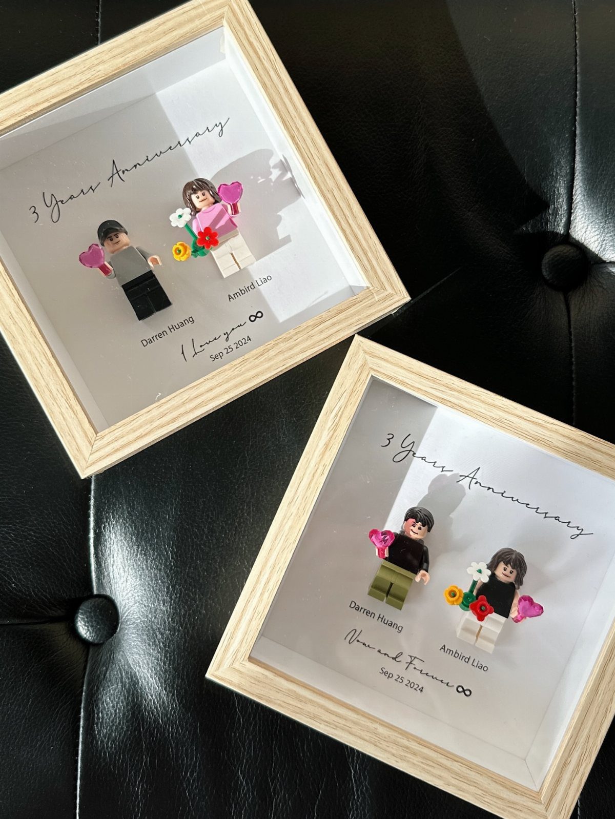 Custom LEGO couple minifigures in wooden shadow boxes resting on black leather upholstery.