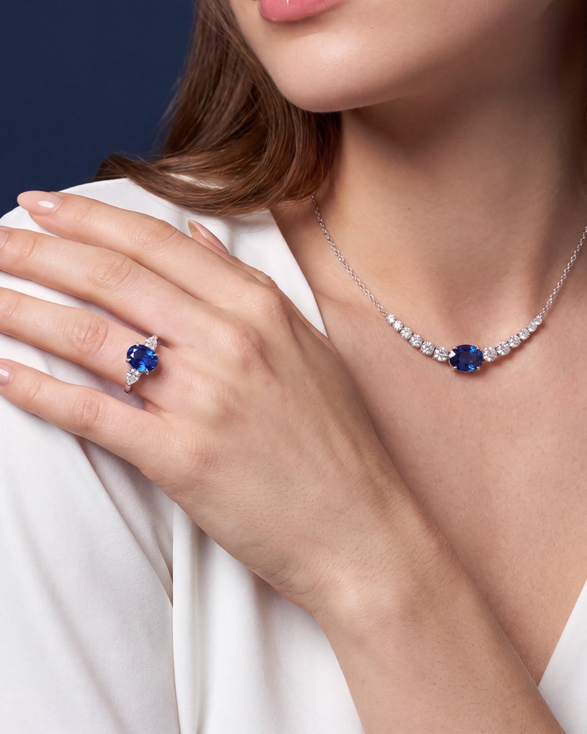 Sapphire necklace and ring worn by a woman in a white blouse.