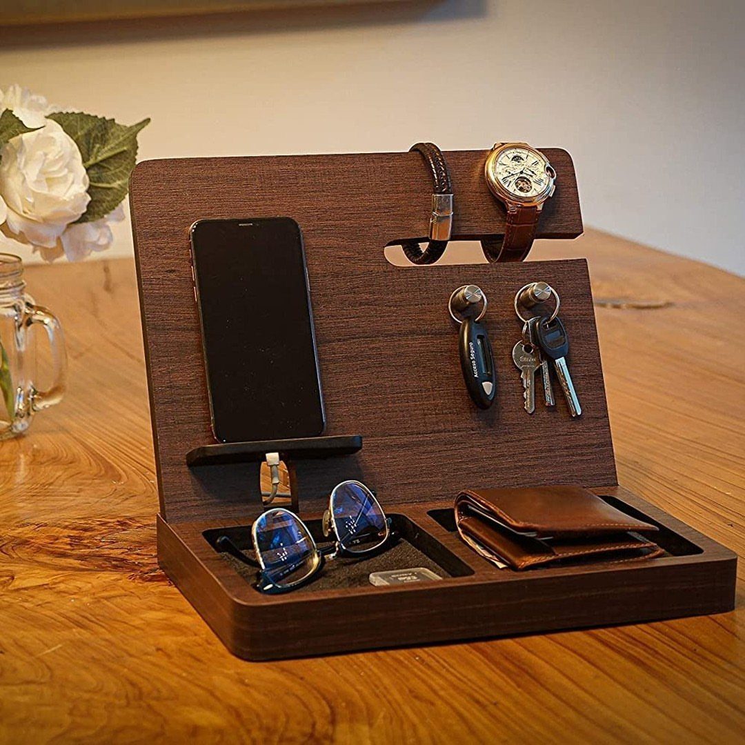 Wooden docking station holding a smartphone, watch, keys, sunglasses, and a leather wallet.