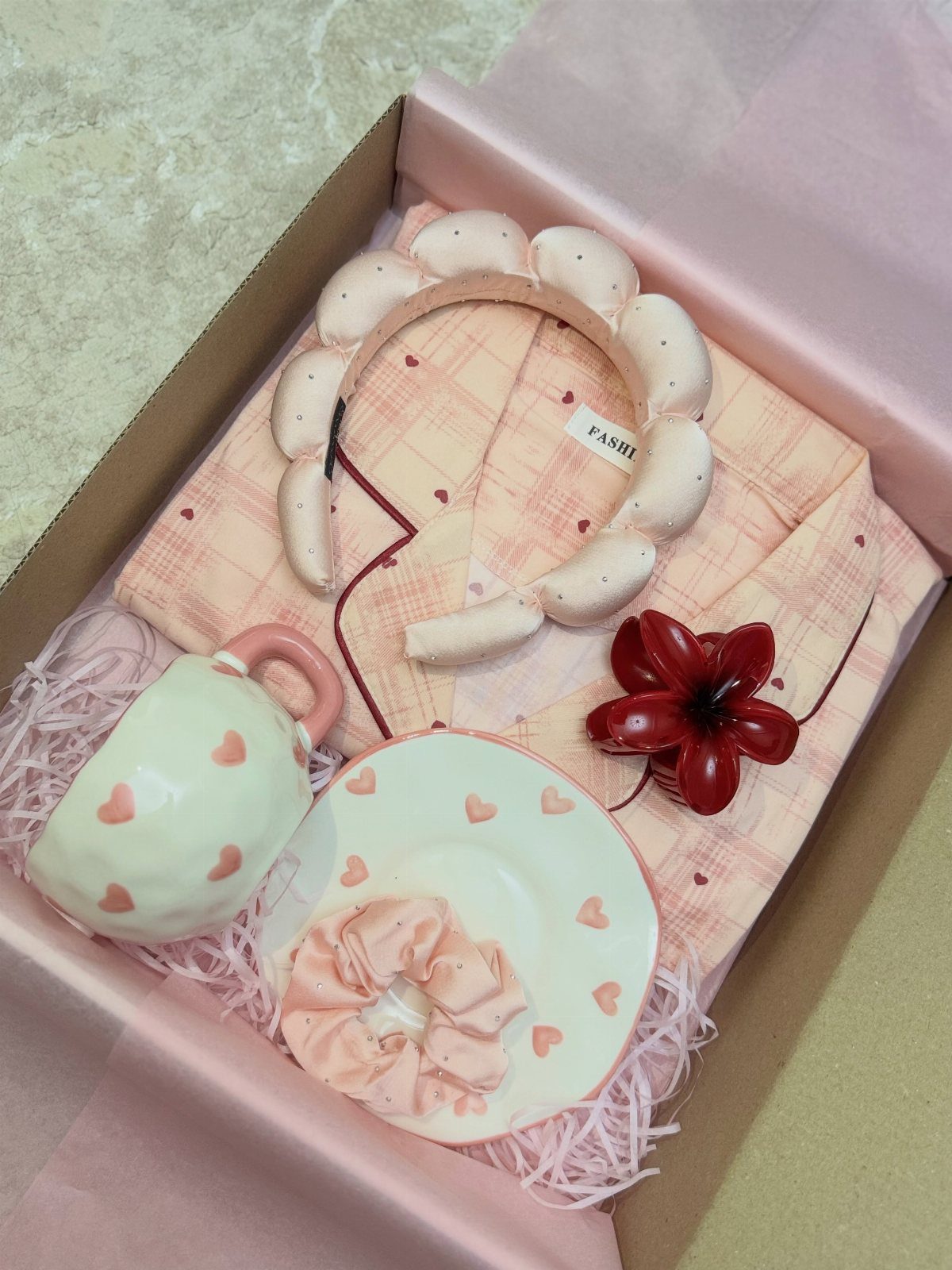 Gift box with pink checkered fabric, white padded headband, and heart-patterned ceramic mug.