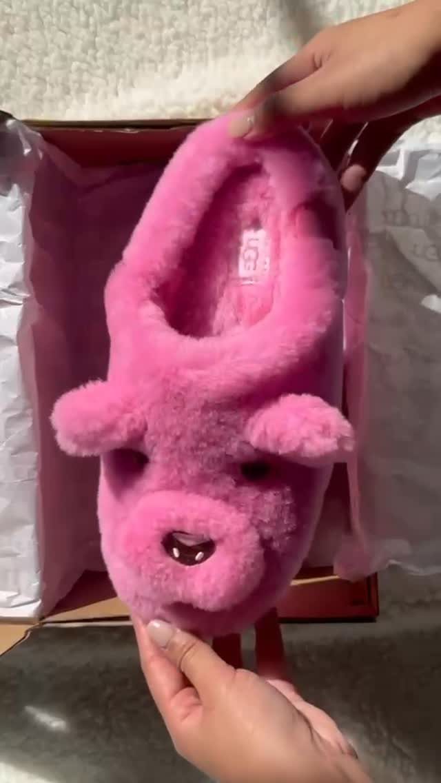 Pink fluffy animal-shaped slipper held over a cardboard shipping box with tissue paper.