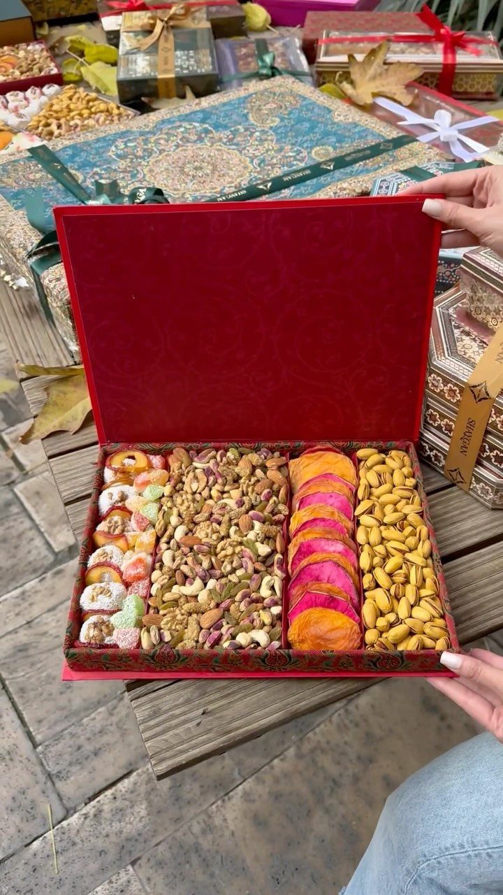 Red velvet gift box filled with assorted nuts and dried fruits on a table