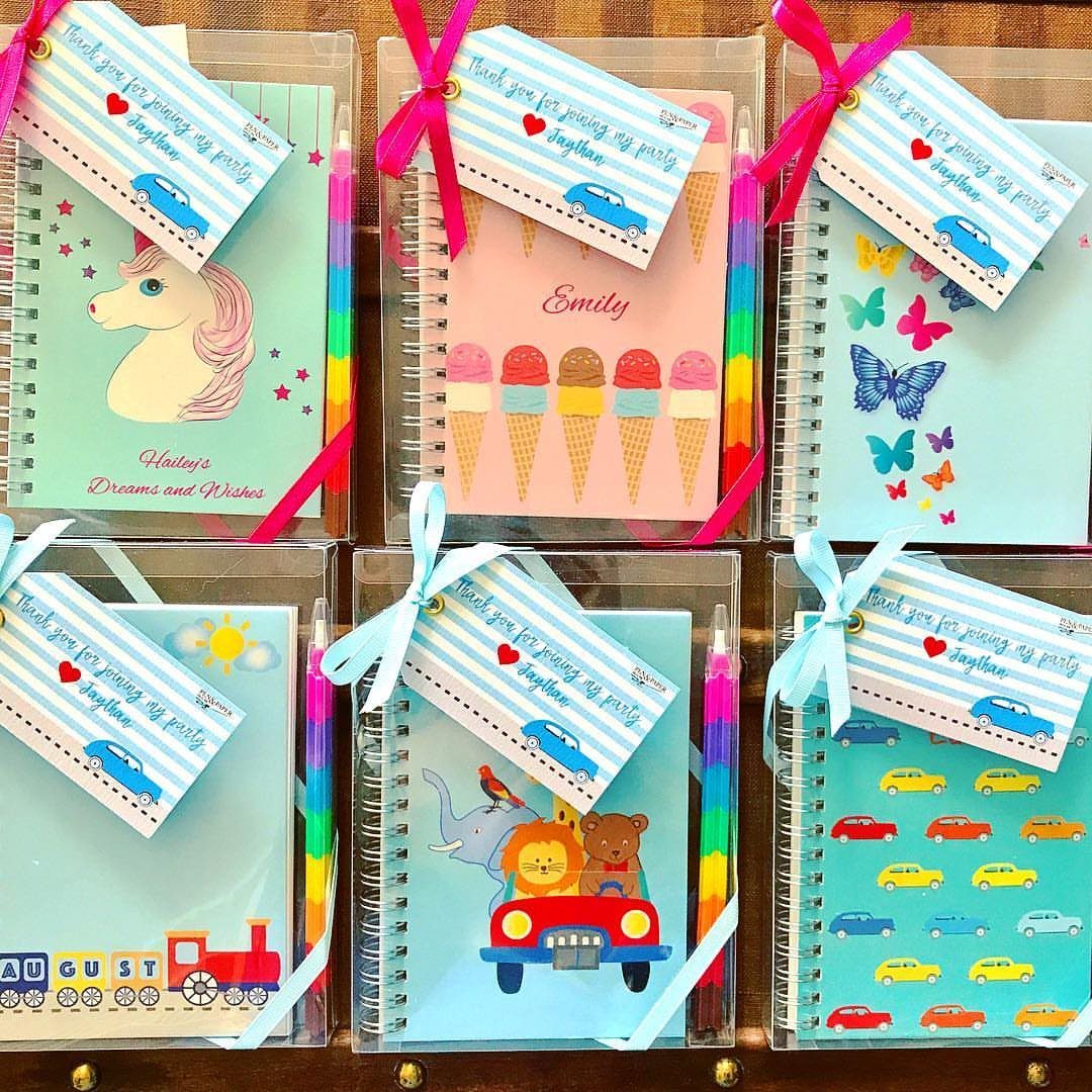 Six colorful personalized spiral notebooks in clear gift bags with ribbons and tags.