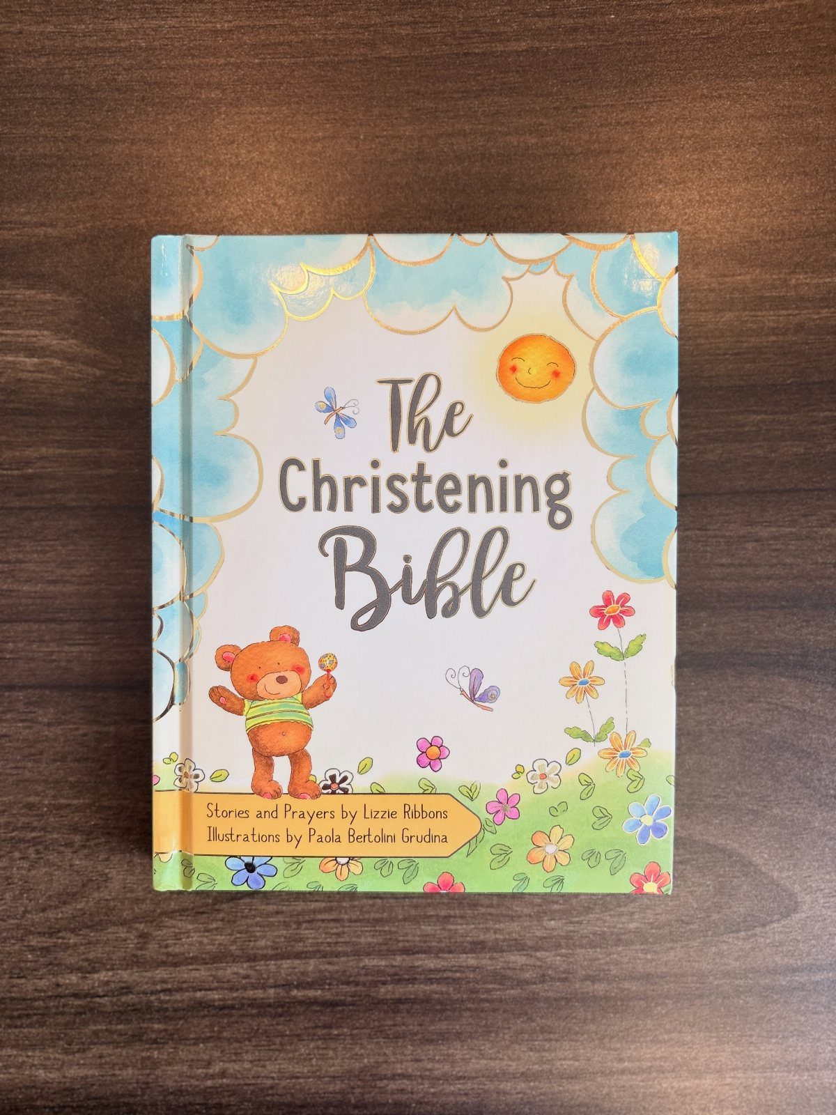 The Christening Bible book with a teddy bear illustration on a wooden table