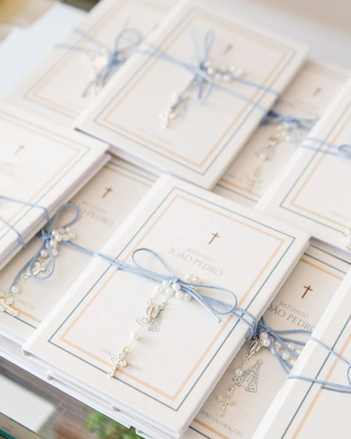 White christening memory books tied with blue ribbons and silver cross charms.