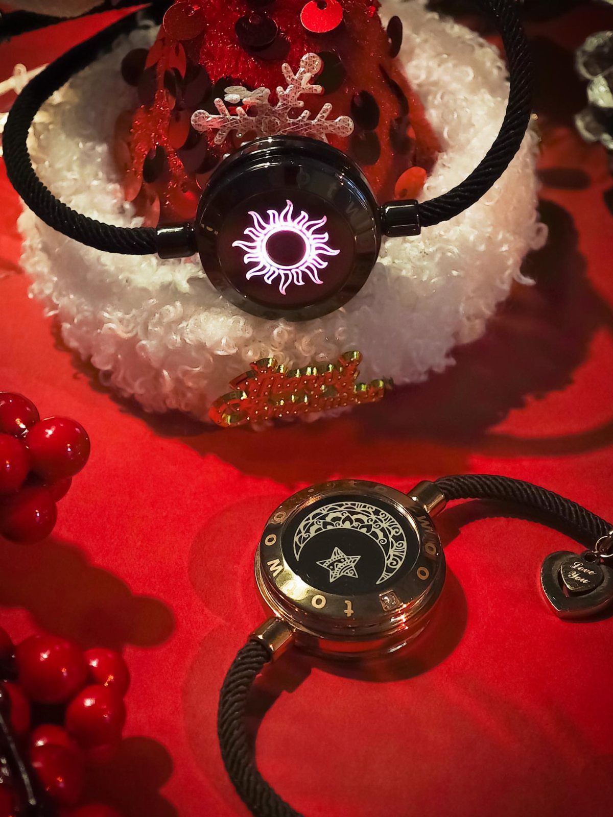 Two black braided cord bracelets with sun and moon pendants on red background