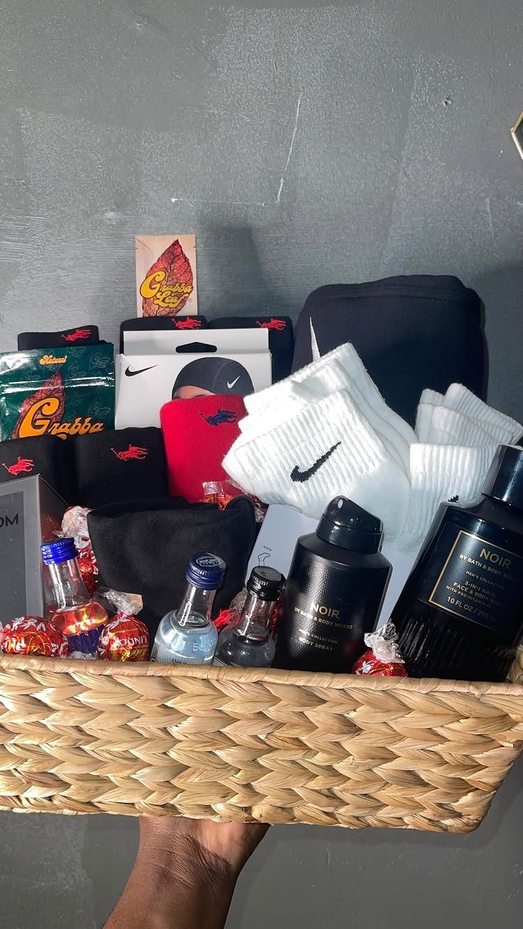 Woven gift basket containing Nike socks, cologne, liquor bottles, and a black beanie.