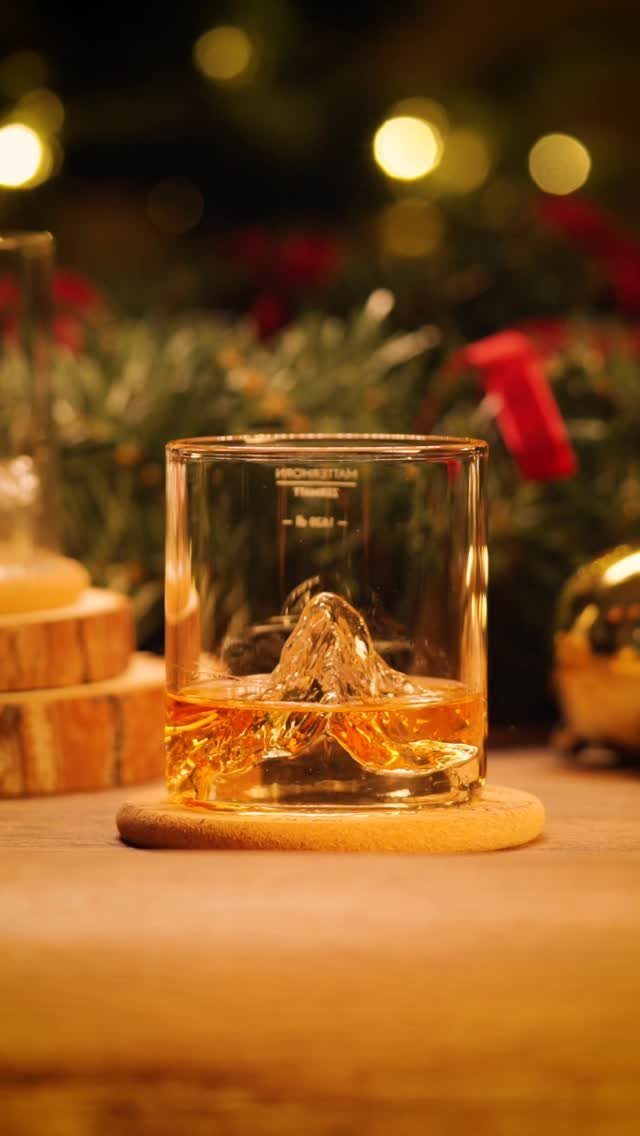 Glass of whiskey with mountain ice cube on a festive Christmas background