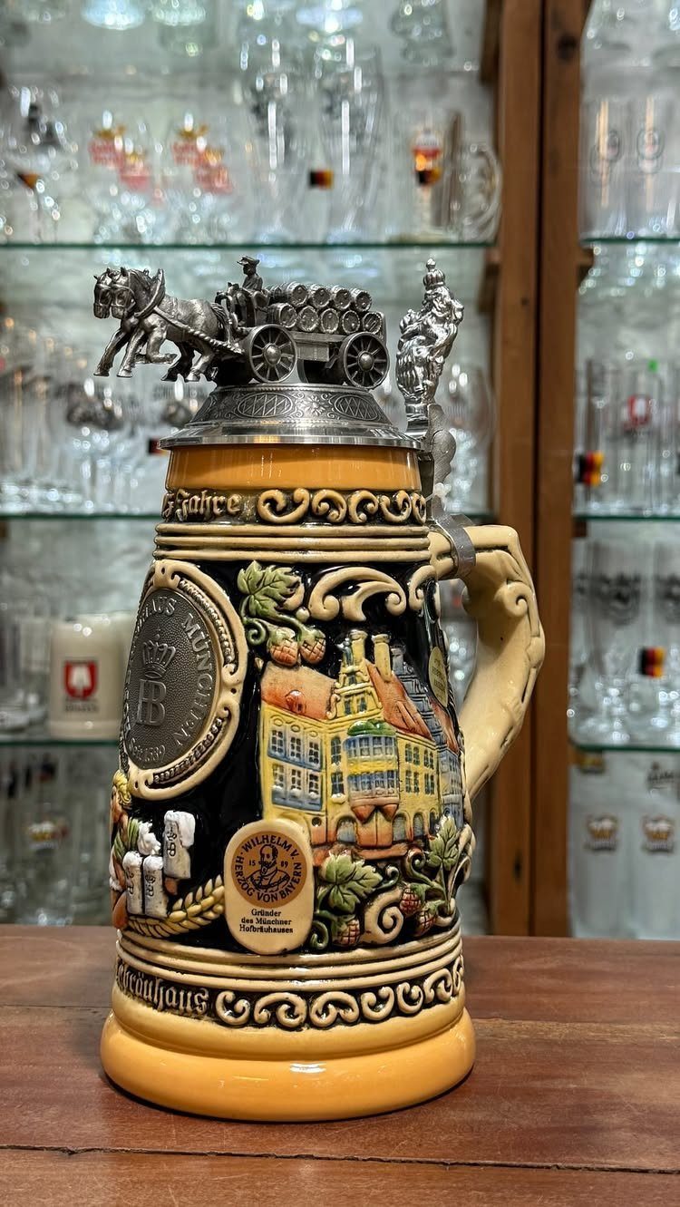 Decorative ceramic beer stein with a silver horse-drawn carriage lid on wooden table