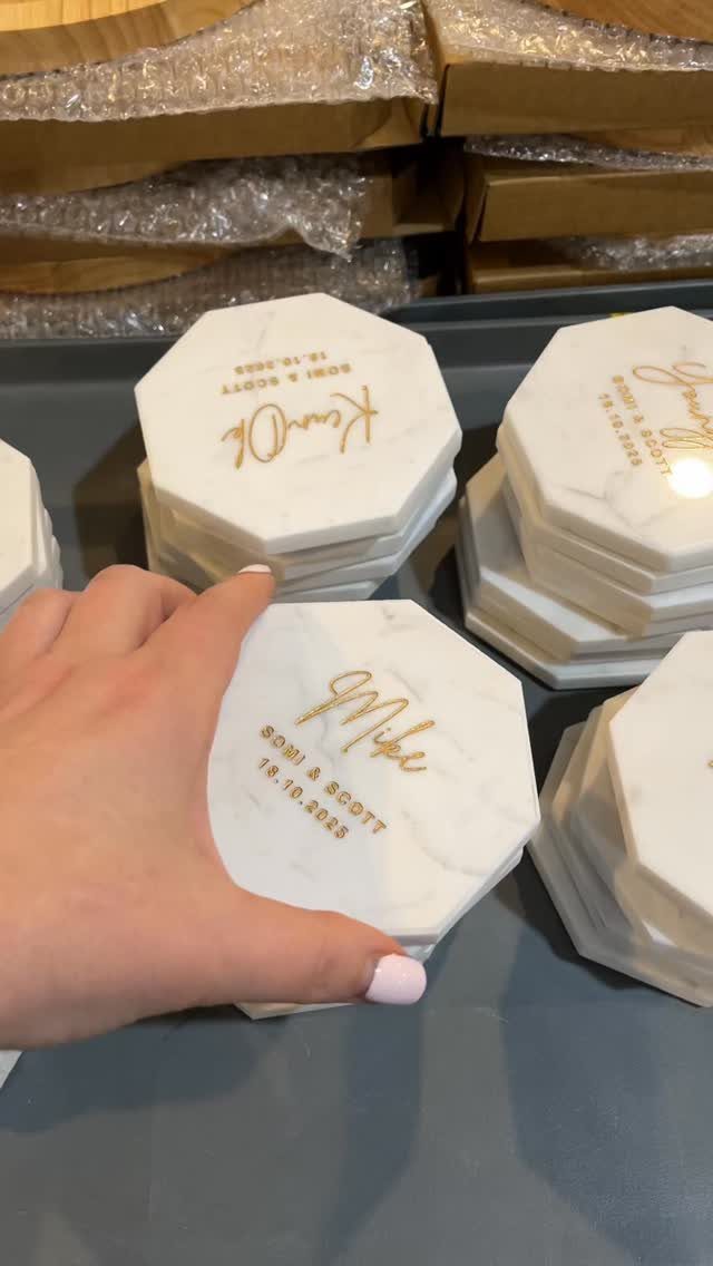 White hexagonal marble coasters with gold personalized names and dates for a couple.