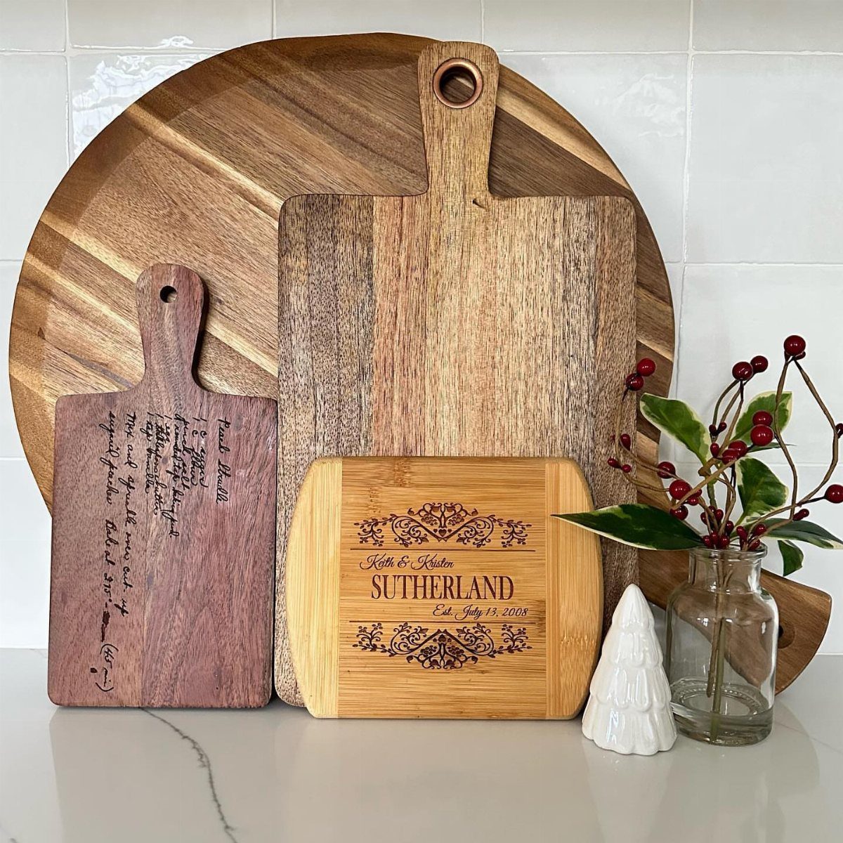 Wooden cutting boards with personalized engravings and festive holiday decorations on a counter