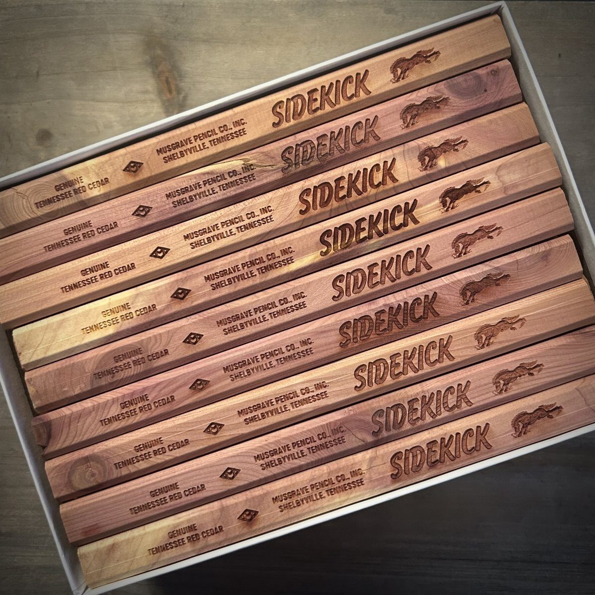 Flat wooden carpenter pencils branded with Sidekick logo in a grey storage box