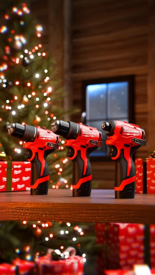 Three red cordless power drills on a wooden shelf with a Christmas tree background