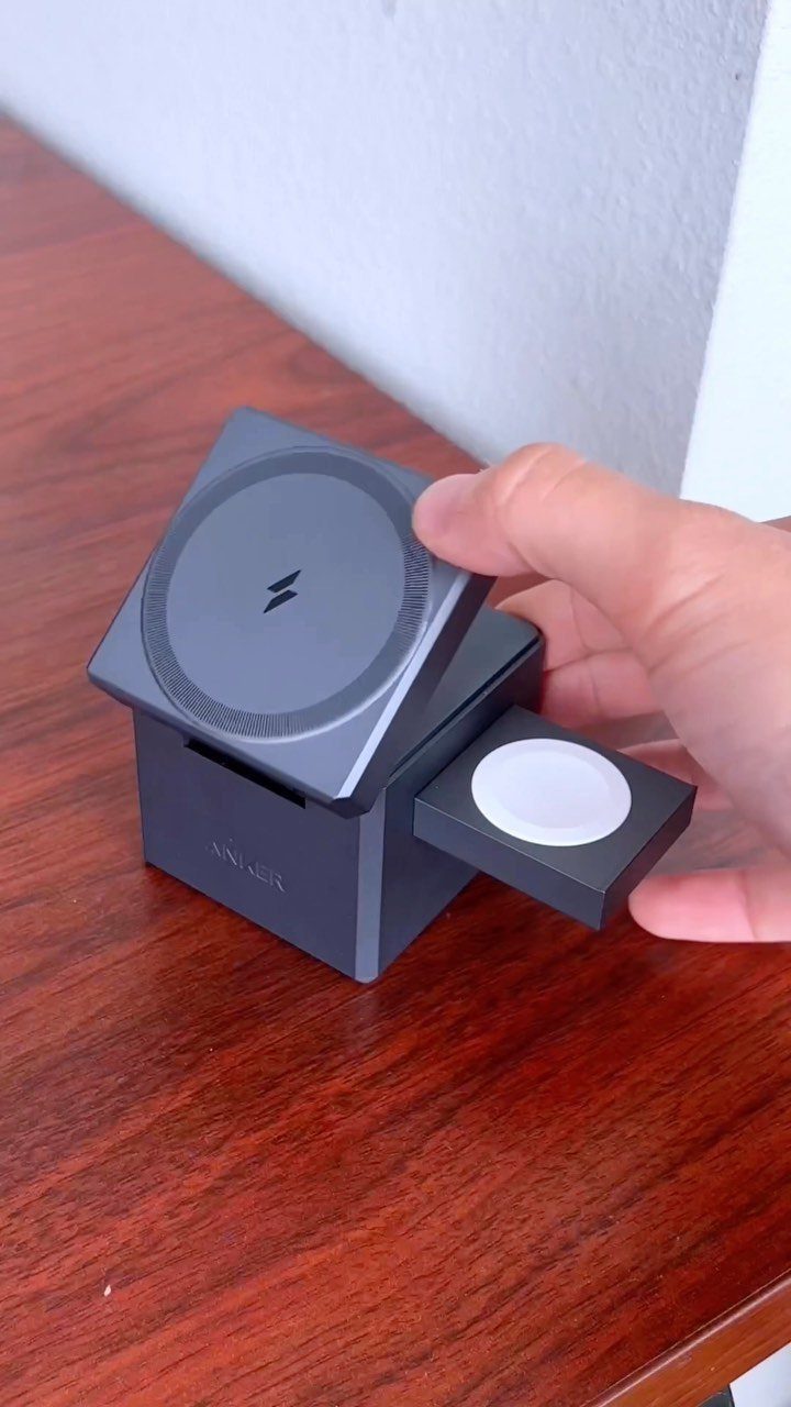 Black electronic charging station on a wooden table being touched by a hand